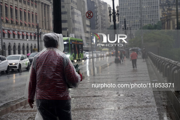 People walk with their umbrellas on a cloudy and rainy day in the center of Sao Paulo, Brazil, on December 10, 2024. 