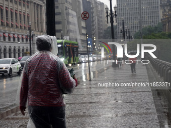 People walk with their umbrellas on a cloudy and rainy day in the center of Sao Paulo, Brazil, on December 10, 2024. (