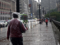 People walk with their umbrellas on a cloudy and rainy day in the center of Sao Paulo, Brazil, on December 10, 2024. (