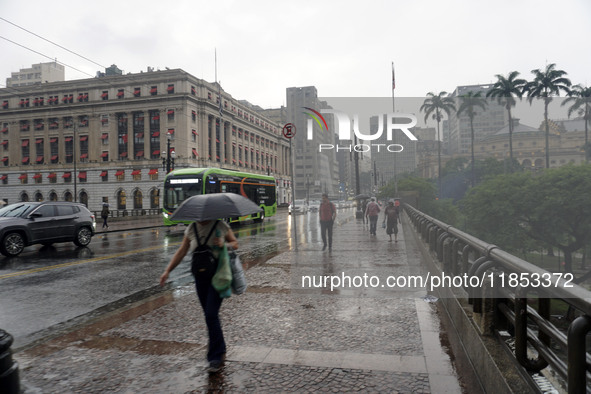 People walk with their umbrellas on a cloudy and rainy day in the center of Sao Paulo, Brazil, on December 10, 2024. 