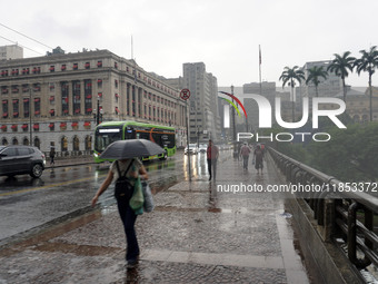 People walk with their umbrellas on a cloudy and rainy day in the center of Sao Paulo, Brazil, on December 10, 2024. (