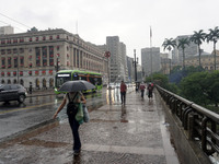 People walk with their umbrellas on a cloudy and rainy day in the center of Sao Paulo, Brazil, on December 10, 2024. (