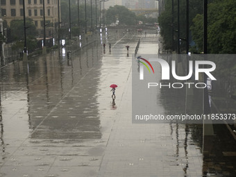 People walk with their umbrellas on a cloudy and rainy day in the center of Sao Paulo, Brazil, on December 10, 2024. (