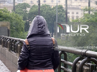 People walk with their umbrellas on a cloudy and rainy day in the center of Sao Paulo, Brazil, on December 10, 2024. (