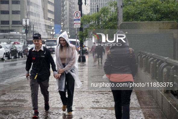 People walk with their umbrellas on a cloudy and rainy day in the center of Sao Paulo, Brazil, on December 10, 2024. 