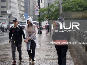 People walk with their umbrellas on a cloudy and rainy day in the center of Sao Paulo, Brazil, on December 10, 2024. (