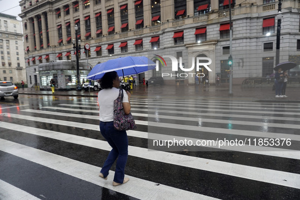 People walk with their umbrellas on a cloudy and rainy day in the center of Sao Paulo, Brazil, on December 10, 2024. 