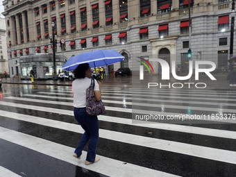 People walk with their umbrellas on a cloudy and rainy day in the center of Sao Paulo, Brazil, on December 10, 2024. (