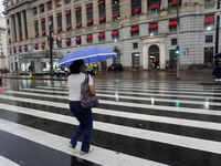 People walk with their umbrellas on a cloudy and rainy day in the center of Sao Paulo, Brazil, on December 10, 2024. (