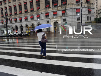 People walk with their umbrellas on a cloudy and rainy day in the center of Sao Paulo, Brazil, on December 10, 2024. (