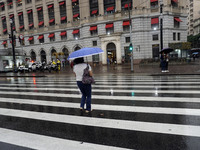 People walk with their umbrellas on a cloudy and rainy day in the center of Sao Paulo, Brazil, on December 10, 2024. (