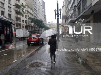 People walk with their umbrellas on a cloudy and rainy day in the center of Sao Paulo, Brazil, on December 10, 2024. (