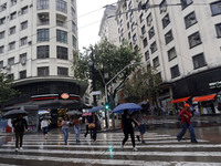 People walk with their umbrellas on a cloudy and rainy day in the center of Sao Paulo, Brazil, on December 10, 2024. (