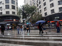 People walk with their umbrellas on a cloudy and rainy day in the center of Sao Paulo, Brazil, on December 10, 2024. (