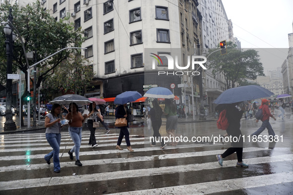 People walk with their umbrellas on a cloudy and rainy day in the center of Sao Paulo, Brazil, on December 10, 2024. 