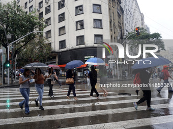 People walk with their umbrellas on a cloudy and rainy day in the center of Sao Paulo, Brazil, on December 10, 2024. (