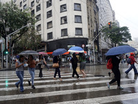 People walk with their umbrellas on a cloudy and rainy day in the center of Sao Paulo, Brazil, on December 10, 2024. (