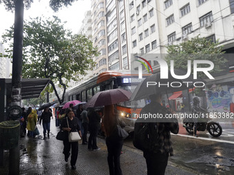 People walk with their umbrellas on a cloudy and rainy day in the center of Sao Paulo, Brazil, on December 10, 2024. (