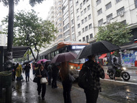 People walk with their umbrellas on a cloudy and rainy day in the center of Sao Paulo, Brazil, on December 10, 2024. (