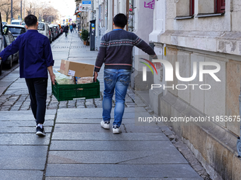 Two Asian men, employees of an Asian snack bar, carry a green crate filled with food and supplies in Dresden, Saxony, Germany, on March 23,...