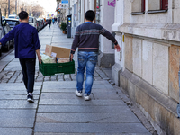 Two Asian men, employees of an Asian snack bar, carry a green crate filled with food and supplies in Dresden, Saxony, Germany, on March 23,...