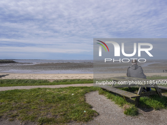 A man sits on a bench on the shore of the Wadden Sea, looking at the ebb of the tide in Esbjerg, Denmark, on April 28, 2024 (