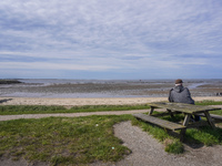 A man sits on a bench on the shore of the Wadden Sea, looking at the ebb of the tide in Esbjerg, Denmark, on April 28, 2024 (