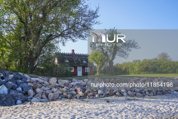 An old Danish wooden house with a thatched roof is on the seashore in Kongebro Middelfart, Fyn, Denmark, on May 3, 2024. 