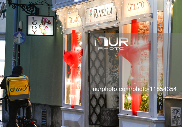 KRAKOW, POLAND - DECEMBER 10:   
A Glovo courier waits for his order outside a gelato shop in the historic Old Town, on December 10, 2024 in...