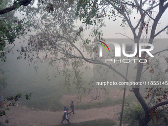 People exercise in the morning on a ground during a cold, foggy day in Siliguri, India, on December 11, 2024. (