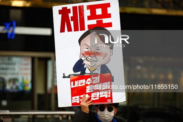 A protester holds a sign reading 'Arrest Traitor Yoon Suk-yeol, Impeach Immediately' during a solo demonstration in front of the People Powe...