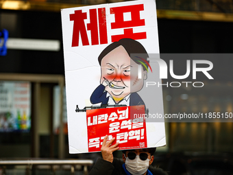 A protester holds a sign reading 'Arrest Traitor Yoon Suk-yeol, Impeach Immediately' during a solo demonstration in front of the People Powe...