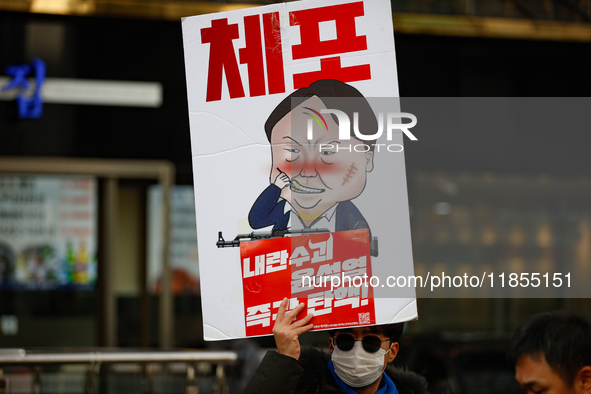 A protester holds a sign reading 'Arrest Traitor Yoon Suk-yeol, Impeach Immediately' during a solo demonstration in front of the People Powe...