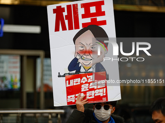 A protester holds a sign reading 'Arrest Traitor Yoon Suk-yeol, Impeach Immediately' during a solo demonstration in front of the People Powe...