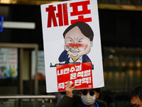 A protester holds a sign reading 'Arrest Traitor Yoon Suk-yeol, Impeach Immediately' during a solo demonstration in front of the People Powe...