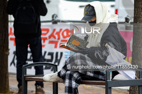 A participant in a rally calling for the impeachment of President Yoon Suk-yeol reads ''Human Acts (The Boy is Coming)'' by 2024 Nobel Prize...