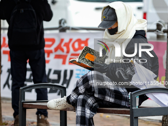 A participant in a rally calling for the impeachment of President Yoon Suk-yeol reads ''Human Acts (The Boy is Coming)'' by 2024 Nobel Prize...