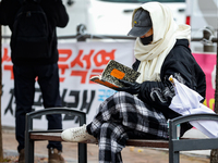 A participant in a rally calling for the impeachment of President Yoon Suk-yeol reads ''Human Acts (The Boy is Coming)'' by 2024 Nobel Prize...