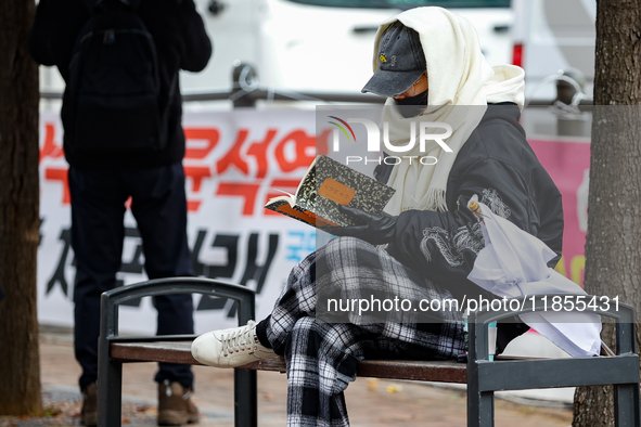 A participant in a rally calling for the impeachment of President Yoon Suk-yeol reads ''Human Acts (The Boy is Coming)'' by 2024 Nobel Prize...