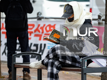 A participant in a rally calling for the impeachment of President Yoon Suk-yeol reads ''Human Acts (The Boy is Coming)'' by 2024 Nobel Prize...