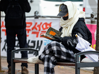 A participant in a rally calling for the impeachment of President Yoon Suk-yeol reads ''Human Acts (The Boy is Coming)'' by 2024 Nobel Prize...