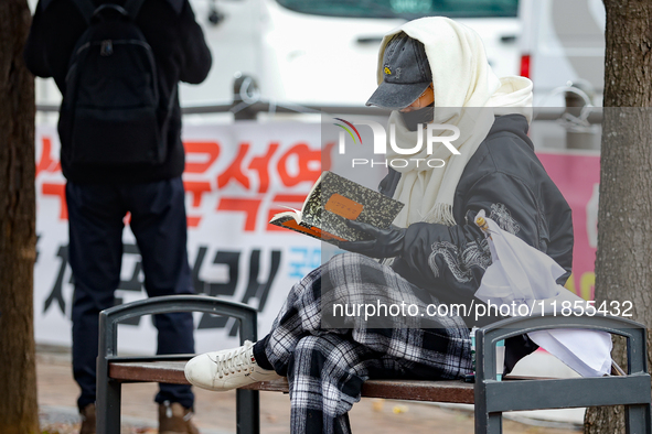 A participant in a rally calling for the impeachment of President Yoon Suk-yeol reads ''Human Acts (The Boy is Coming)'' by 2024 Nobel Prize...