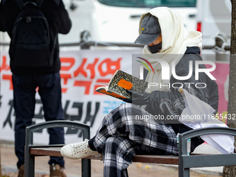 A participant in a rally calling for the impeachment of President Yoon Suk-yeol reads ''Human Acts (The Boy is Coming)'' by 2024 Nobel Prize...