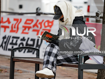 A participant in a rally calling for the impeachment of President Yoon Suk-yeol reads ''Human Acts (The Boy is Coming)'' by 2024 Nobel Prize...