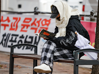 A participant in a rally calling for the impeachment of President Yoon Suk-yeol reads ''Human Acts (The Boy is Coming)'' by 2024 Nobel Prize...