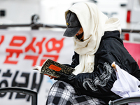 A participant in a rally calling for the impeachment of President Yoon Suk-yeol reads ''Human Acts (The Boy is Coming)'' by 2024 Nobel Prize...