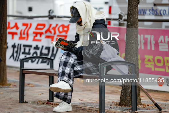 A participant in a rally calling for the impeachment of President Yoon Suk-yeol reads ''Human Acts (The Boy is Coming)'' by 2024 Nobel Prize...