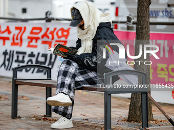 A participant in a rally calling for the impeachment of President Yoon Suk-yeol reads ''Human Acts (The Boy is Coming)'' by 2024 Nobel Prize...