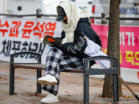 A participant in a rally calling for the impeachment of President Yoon Suk-yeol reads ''Human Acts (The Boy is Coming)'' by 2024 Nobel Prize...