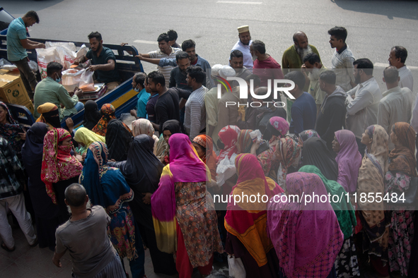 People wait in a long queue to buy government-subsidized food in Dhaka, Bangladesh, on December 10, 2024. 